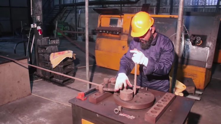 Worker bending reinforcement steel on a bar-bending machine at the K A Piyasena & Sons factory